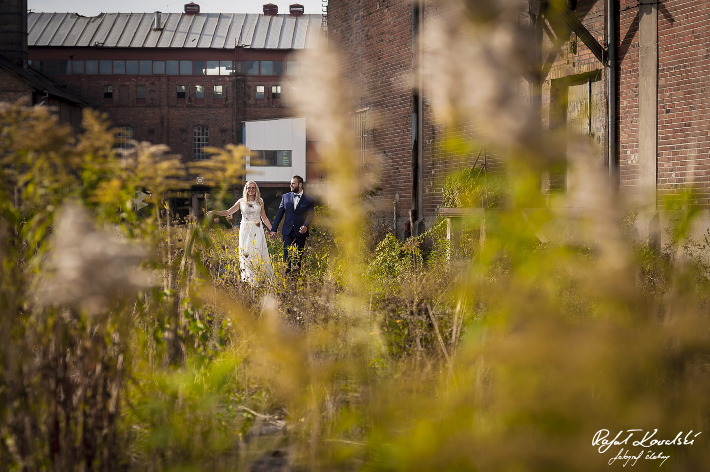 plener ślubny w starej fabryce - spacer młodej pary po dziedzińcu