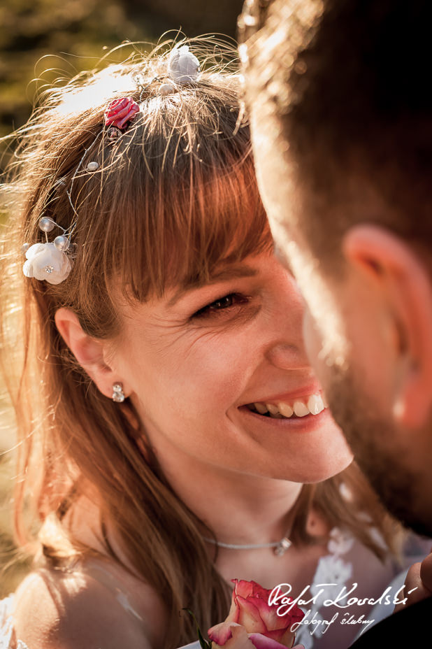 ujęcie z bliska na roześmianą buzię panny młodej wpatrującej się w oczy męża na plenerze ślubnym w Gdyni