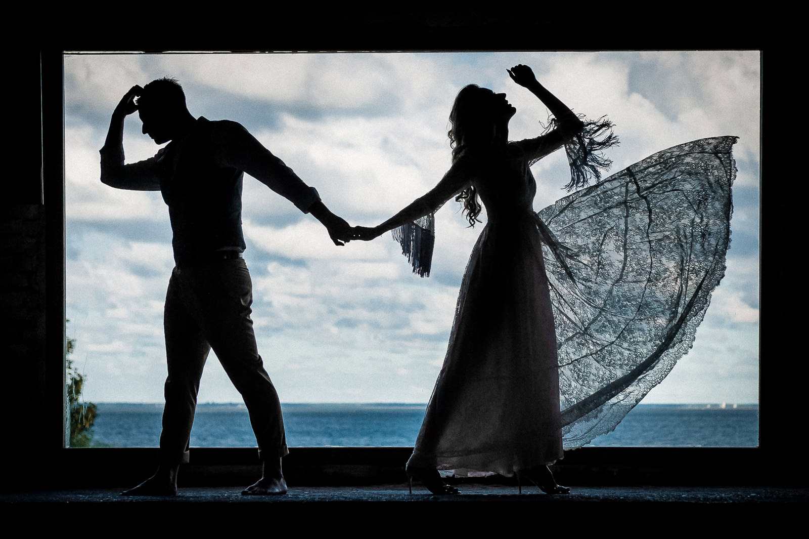 Pełne ekspresji ujęcie sylwetek pary młodej na plenerze ślubnym na tle morza